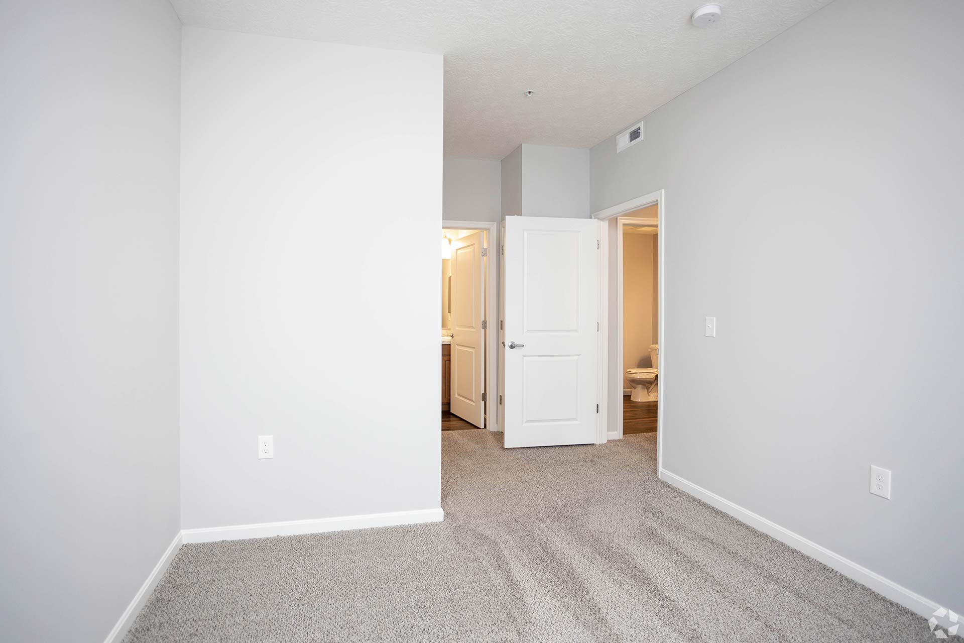 empty room with carpet and white walls at The Adams Pointe