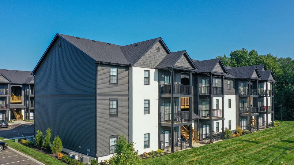 the exterior of an apartment complex with a green lawn at The Adams Pointe